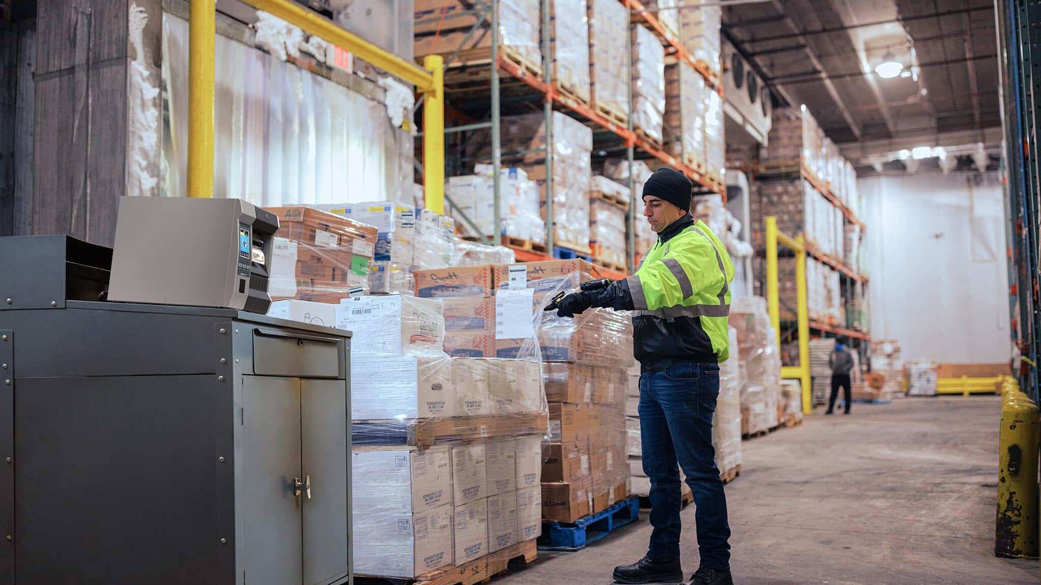 Opérateur en entrepôt frigorifique utilisant une solution d’étiquetage industriel adaptée aux palettes alimentaires et aux contraintes de froid